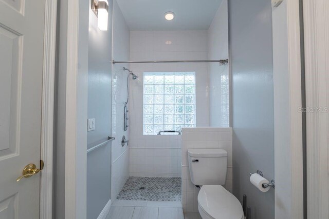 bathroom featuring toilet, tile patterned floors, and tiled shower