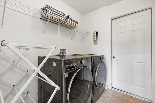 laundry area featuring washer and clothes dryer, a textured ceiling, and tile patterned floors