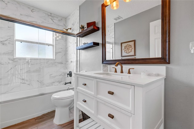 full bathroom featuring tiled shower / bath, vanity, a textured ceiling, hardwood / wood-style flooring, and toilet