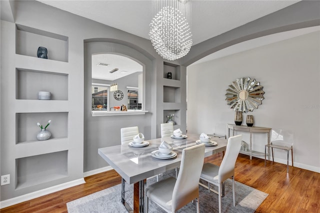 dining room with built in shelves, a chandelier, a textured ceiling, and hardwood / wood-style floors