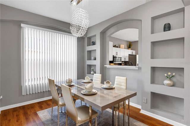 dining room featuring built in features, dark hardwood / wood-style flooring, and a chandelier