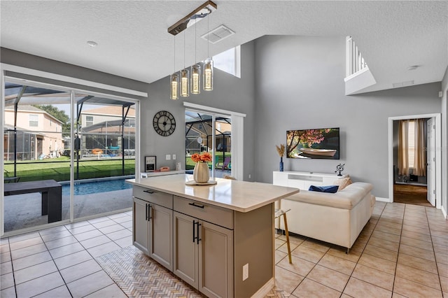 kitchen featuring a kitchen breakfast bar, light tile patterned floors, a textured ceiling, a center island, and decorative light fixtures