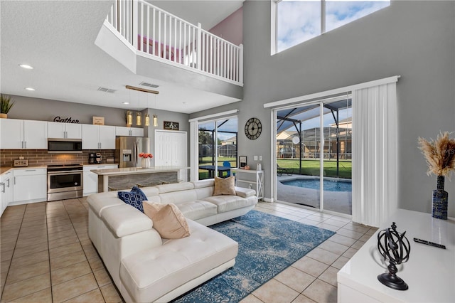 living room featuring a towering ceiling, a textured ceiling, and light tile patterned floors