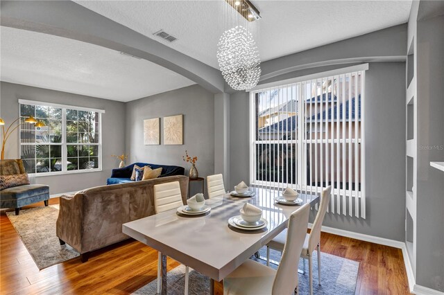 dining area featuring a notable chandelier, a textured ceiling, and hardwood / wood-style flooring