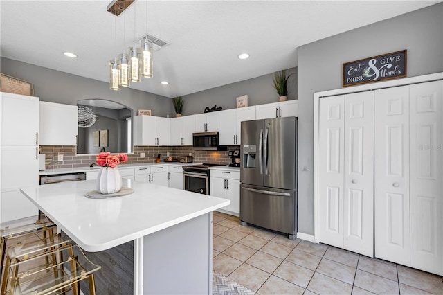 kitchen featuring pendant lighting, a breakfast bar area, white cabinets, a kitchen island, and stainless steel appliances