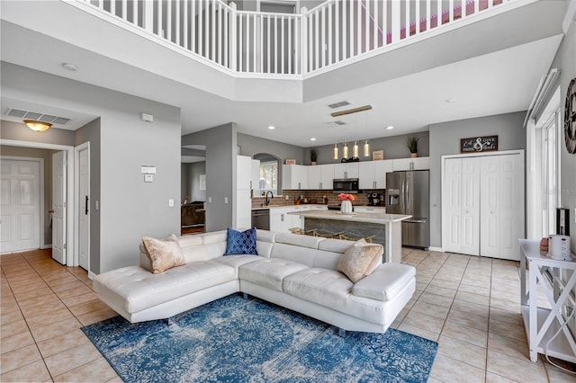 tiled living room with a towering ceiling and sink