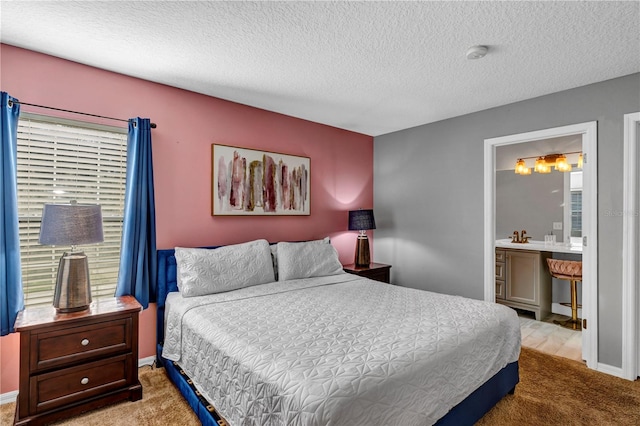 carpeted bedroom featuring ensuite bath and a textured ceiling