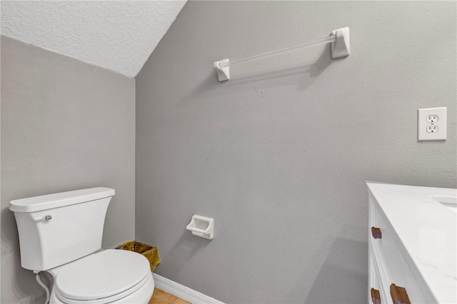 bathroom featuring vaulted ceiling, a textured ceiling, vanity, and toilet