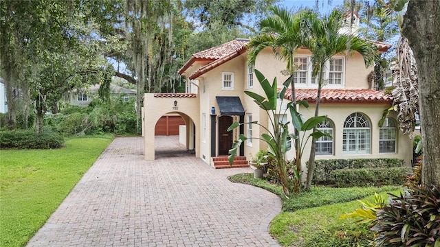 mediterranean / spanish-style home with a garage and a front lawn