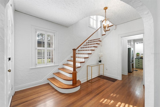 stairway featuring a chandelier, hardwood / wood-style floors, and a textured ceiling