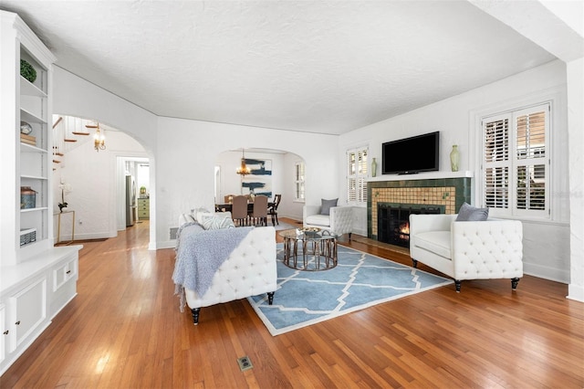 living room featuring a chandelier, a textured ceiling, hardwood / wood-style flooring, and a tiled fireplace