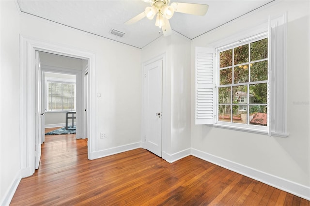 empty room with hardwood / wood-style flooring, plenty of natural light, and ceiling fan