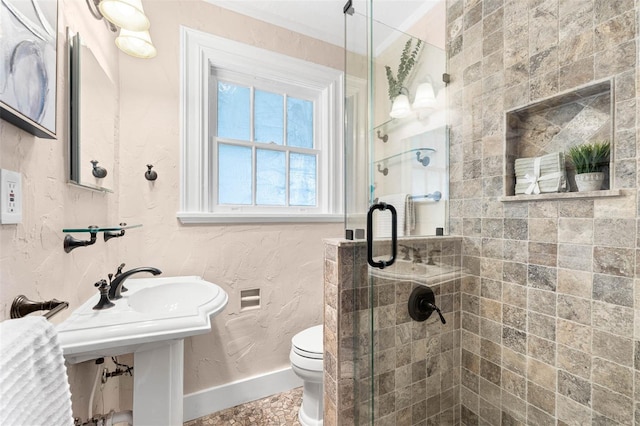 bathroom featuring toilet, a shower with shower door, and sink