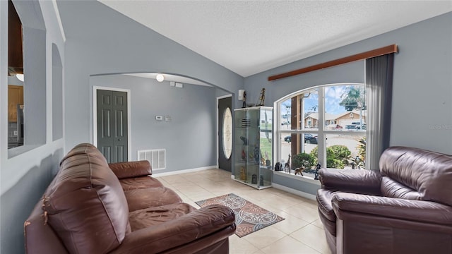 living room with a textured ceiling, lofted ceiling, and light tile patterned floors