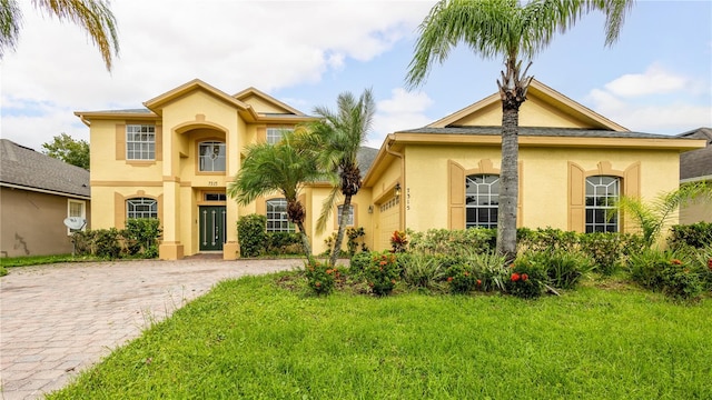 mediterranean / spanish home with a garage and a front lawn