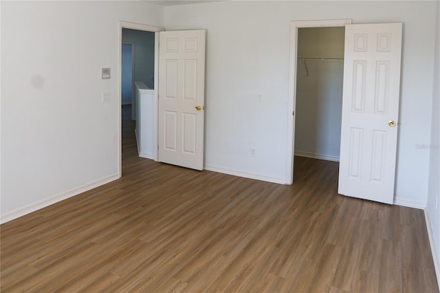 unfurnished bedroom with dark hardwood / wood-style flooring, a spacious closet, and a closet