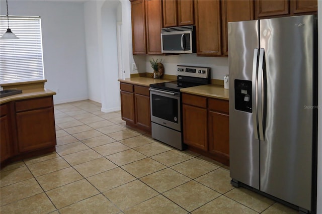 kitchen featuring appliances with stainless steel finishes, light tile patterned floors, and hanging light fixtures