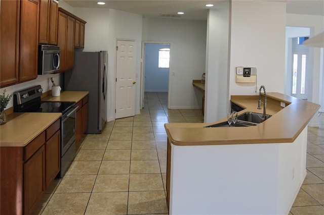 kitchen with kitchen peninsula, sink, light tile patterned floors, and stainless steel appliances