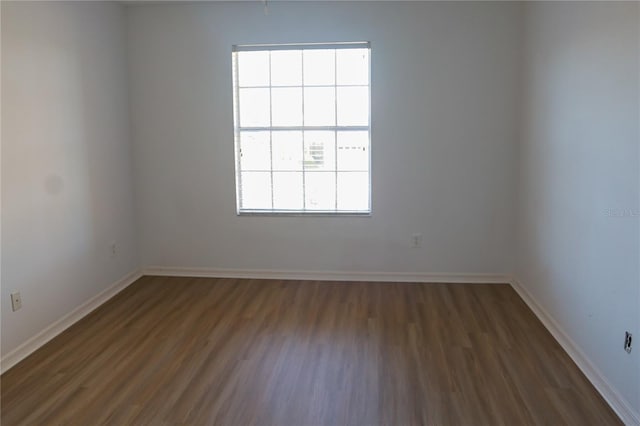 empty room with dark hardwood / wood-style floors and a healthy amount of sunlight