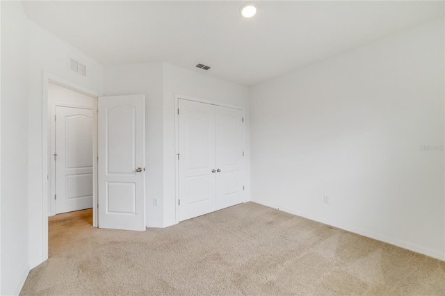 unfurnished bedroom with light carpet and a closet