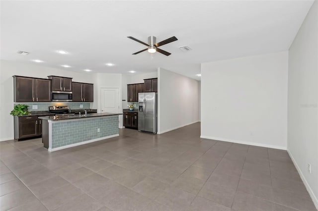 kitchen featuring dark brown cabinetry, stainless steel appliances, a center island with sink, and light tile patterned flooring