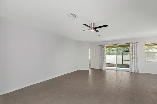 empty room featuring ceiling fan and dark tile patterned flooring