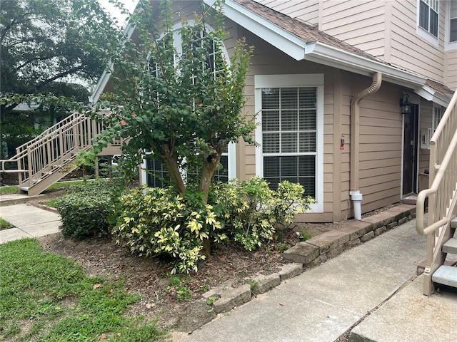 view of property exterior featuring stairs and roof with shingles