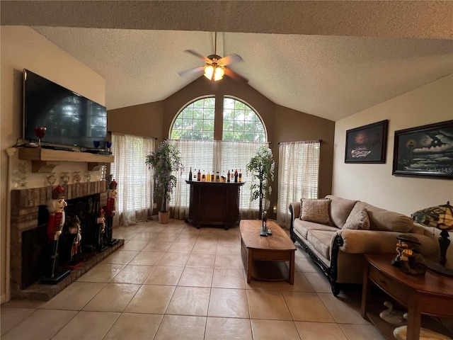 living room featuring ceiling fan, lofted ceiling, light tile patterned floors, a textured ceiling, and a fireplace