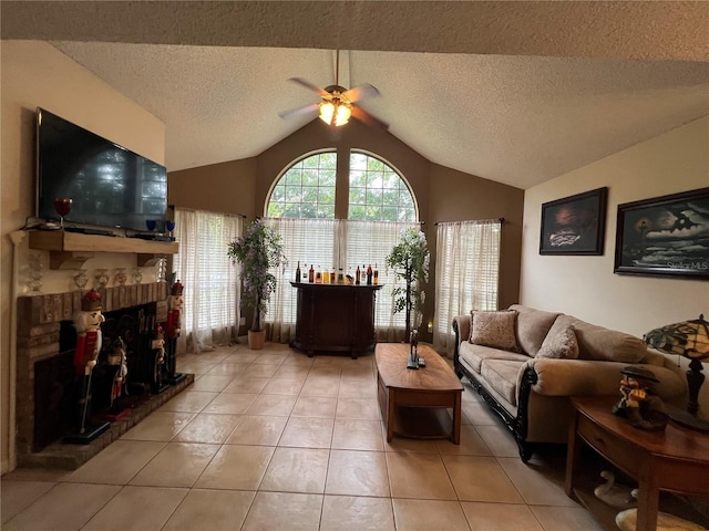 living area featuring light tile patterned floors, a ceiling fan, a fireplace, a textured ceiling, and vaulted ceiling