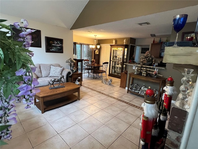 living area featuring a chandelier, light tile patterned floors, visible vents, and lofted ceiling