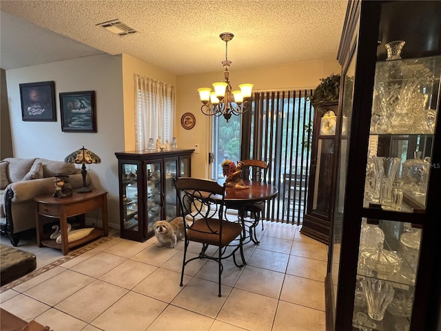 dining room with light tile patterned floors, a notable chandelier, a textured ceiling, and visible vents