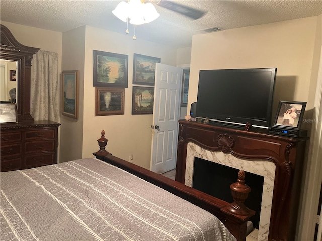 bedroom featuring ceiling fan, a textured ceiling, and a premium fireplace