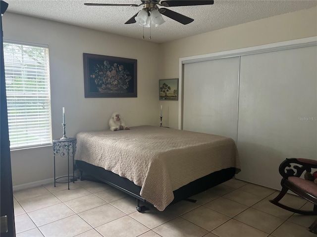 tiled bedroom with a closet, ceiling fan, and a textured ceiling