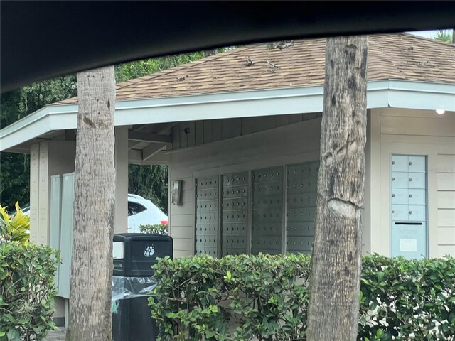 exterior space with roof with shingles and mail area