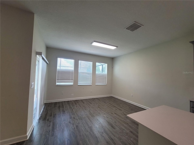 spare room with a textured ceiling and dark wood-type flooring