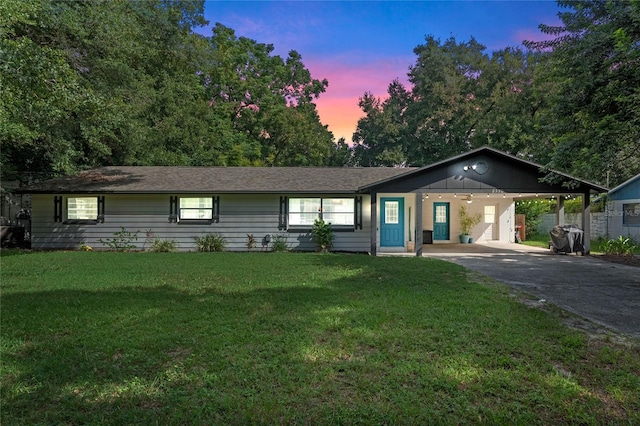 ranch-style home featuring a lawn and a carport