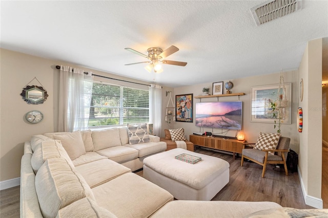 living room with ceiling fan, a textured ceiling, and wood-type flooring