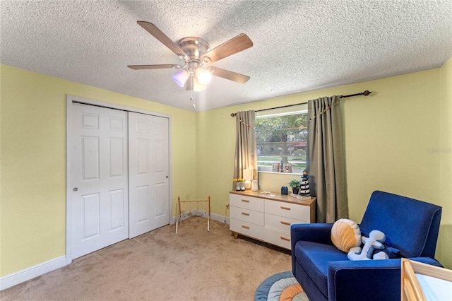 living area with ceiling fan, light colored carpet, and a textured ceiling