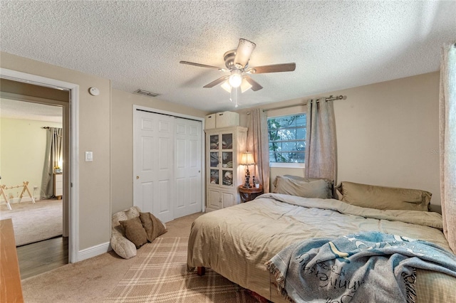 bedroom with carpet floors, a textured ceiling, ceiling fan, and a closet