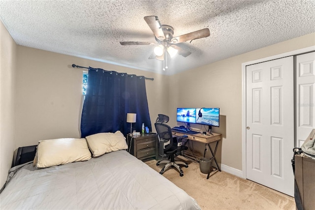 bedroom with a textured ceiling, light carpet, ceiling fan, and a closet