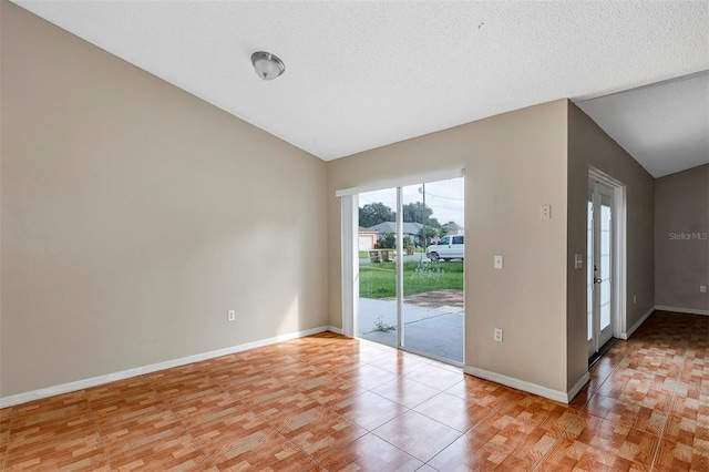 spare room with a textured ceiling, light hardwood / wood-style floors, and vaulted ceiling