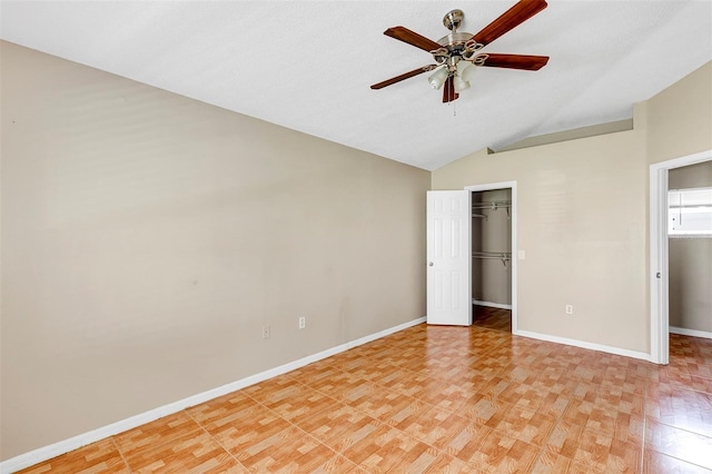 unfurnished bedroom with a closet, a textured ceiling, lofted ceiling, a walk in closet, and ceiling fan