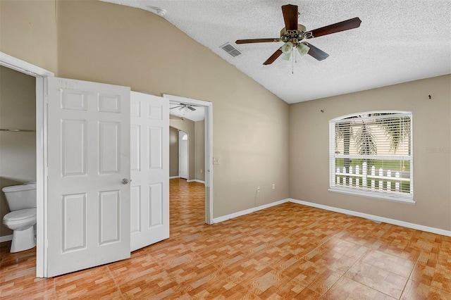 unfurnished bedroom featuring a closet, a textured ceiling, lofted ceiling, ensuite bathroom, and ceiling fan