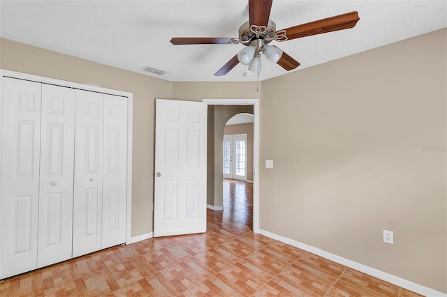 unfurnished bedroom with a textured ceiling, ceiling fan, and a closet