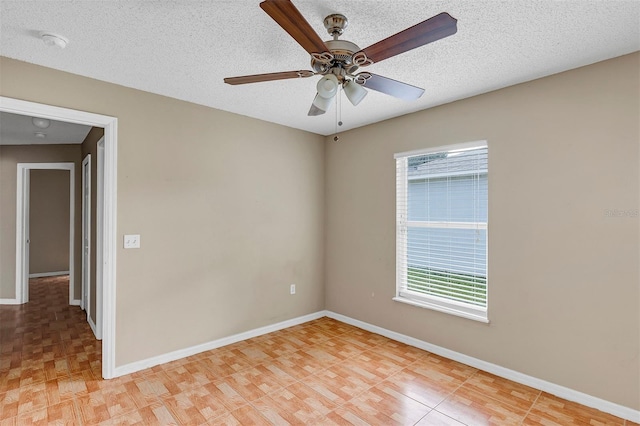 empty room with ceiling fan, plenty of natural light, and a textured ceiling