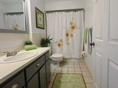 full bathroom with vanity, backsplash, shower / bath combination with curtain, tile patterned flooring, and toilet