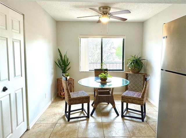 dining space featuring ceiling fan, light tile patterned floors, and a textured ceiling