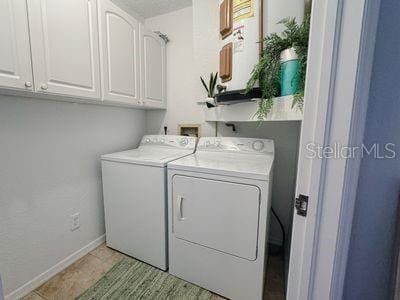 clothes washing area featuring cabinets and separate washer and dryer