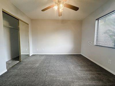 unfurnished bedroom with ceiling fan, a closet, and dark carpet