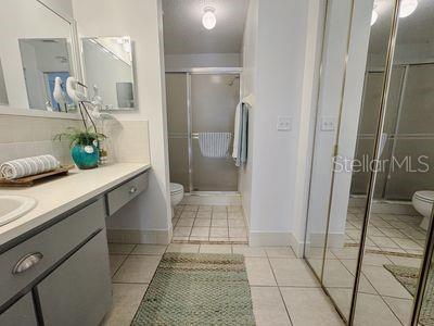 bathroom with toilet, a stall shower, tile patterned flooring, baseboards, and vanity